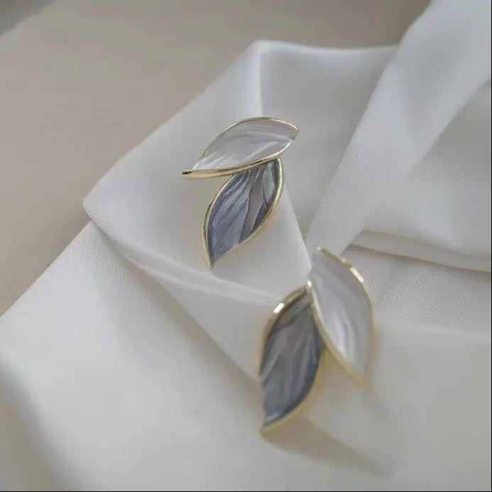 Leaf-shaped earrings with gray and white enamel and gold trim.