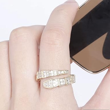 Gold snake ring with cubic zirconia stones on a finger.