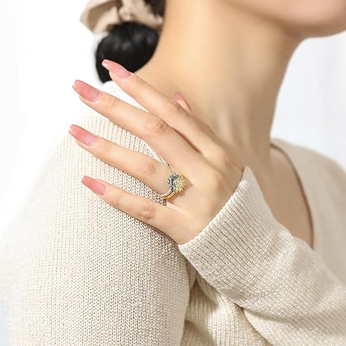 Woman's hand wearing a gold sunflower ring with blue accents.