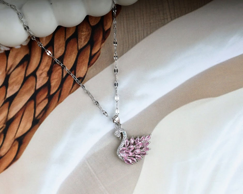 Silver necklace with a swan pendant adorned with pink gemstones.