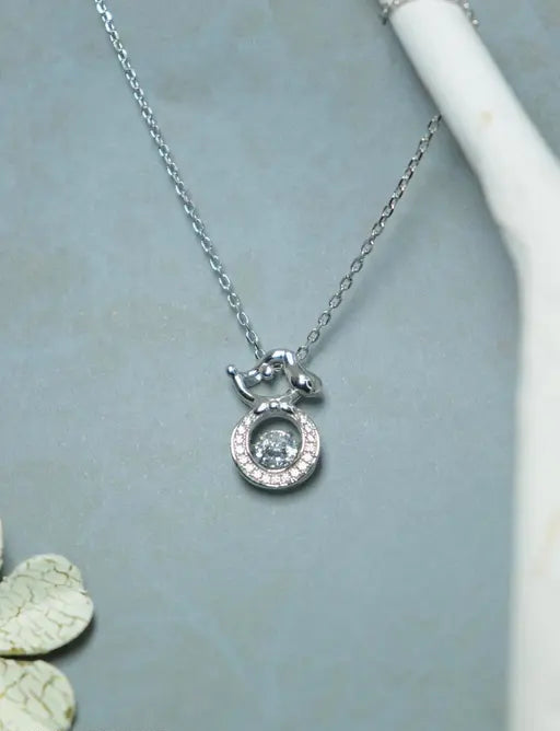 Silver-toned dog pendant necklace with circular crystal halo.