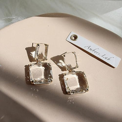 Amber's Lab crystal drop earrings featuring square clear stones and gold settings.