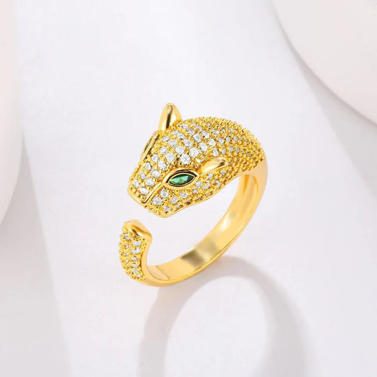 Gold ring featuring a jaguar head design, adorned with cubic zirconia and green stone eyes.